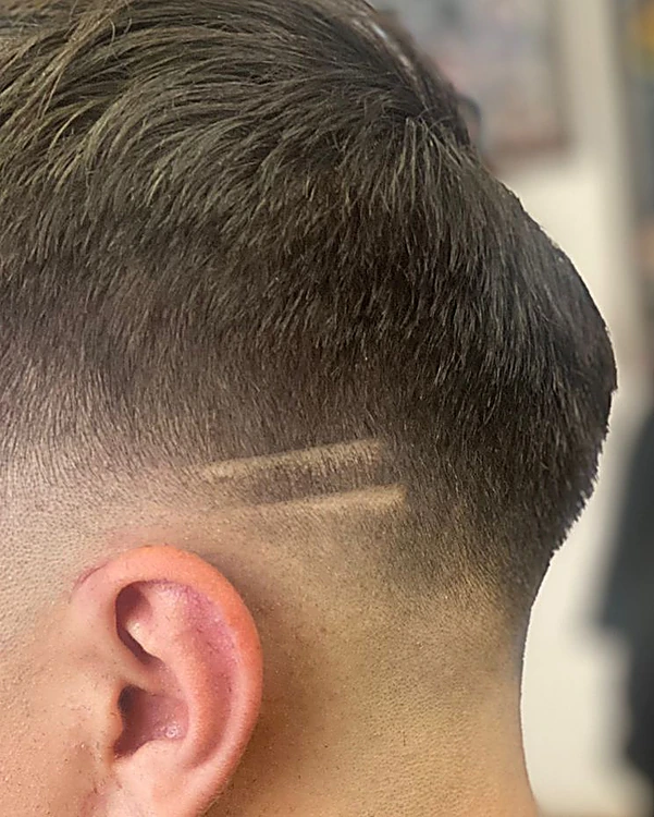 Degradado bajo con una raya rasurada sobre la oreja y arete de cruz